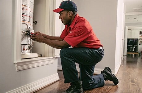A Mr. Rooter Plumbing service professional tightening a bolt on a water heater