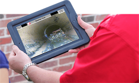 Mr. Rooter technician holding up tablet device with sewer video onscreen.