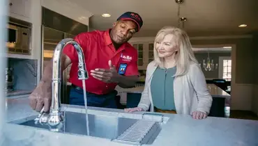 A Mr. Rooter employee displaying how the homeowners faucet is working.