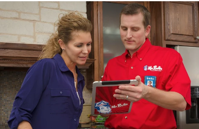 A plumber dressed in the Mr. Rooter Plumbing uniform speaking with a homeowner about an estimate for plumbing in Richardson, TX