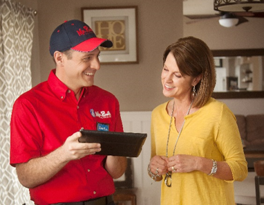 Mr. Rooter technician holding tablet while speaking with customer.