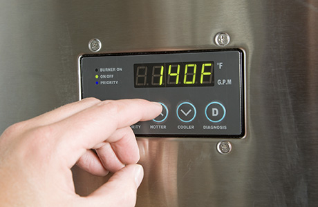 Fingers pressing a button on a tankless water heater in Clearwater, FL