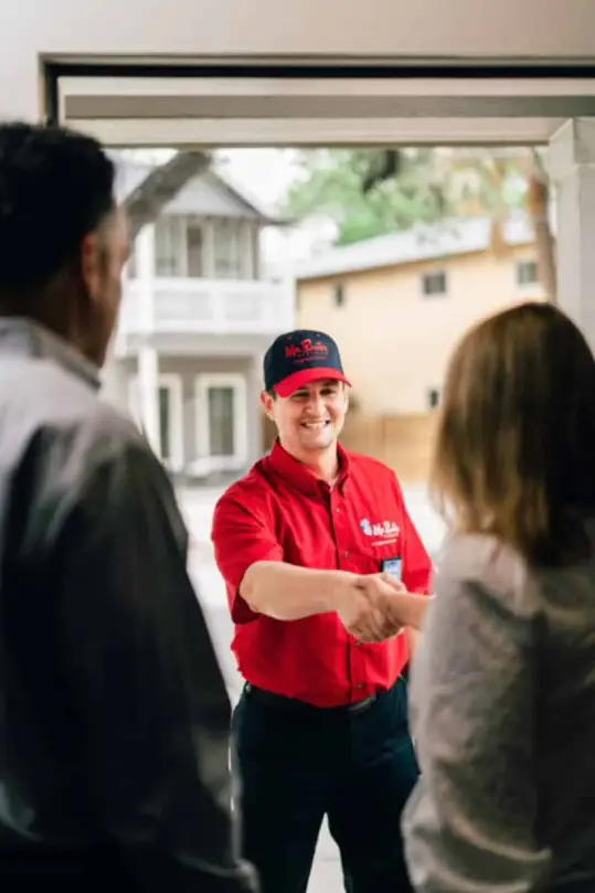 Mr. Rooter plumber greeting customers at the door to their home.