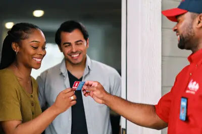 Two happy customers looking at a courteous Mr. Rooter plumber's business card