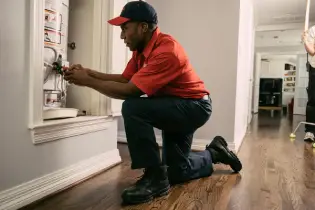 Plumber kneeling working on hot water heater in customer's home