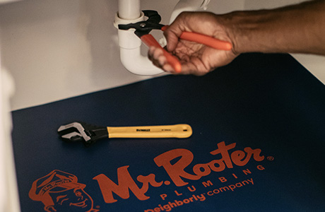 Mr. Rooter plumber fixing a pipe under a sink