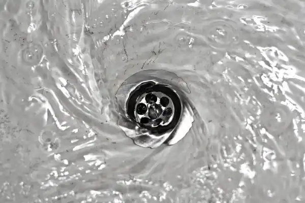 Overhead view of drain with clear water swirling into it.