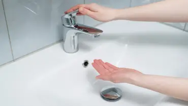 A person turning on a sink faucet to check if there is water