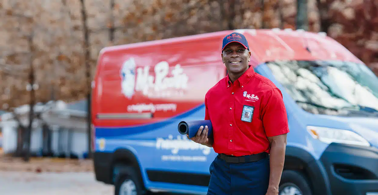 Mr. Rooter professional standing in front of a branded van.