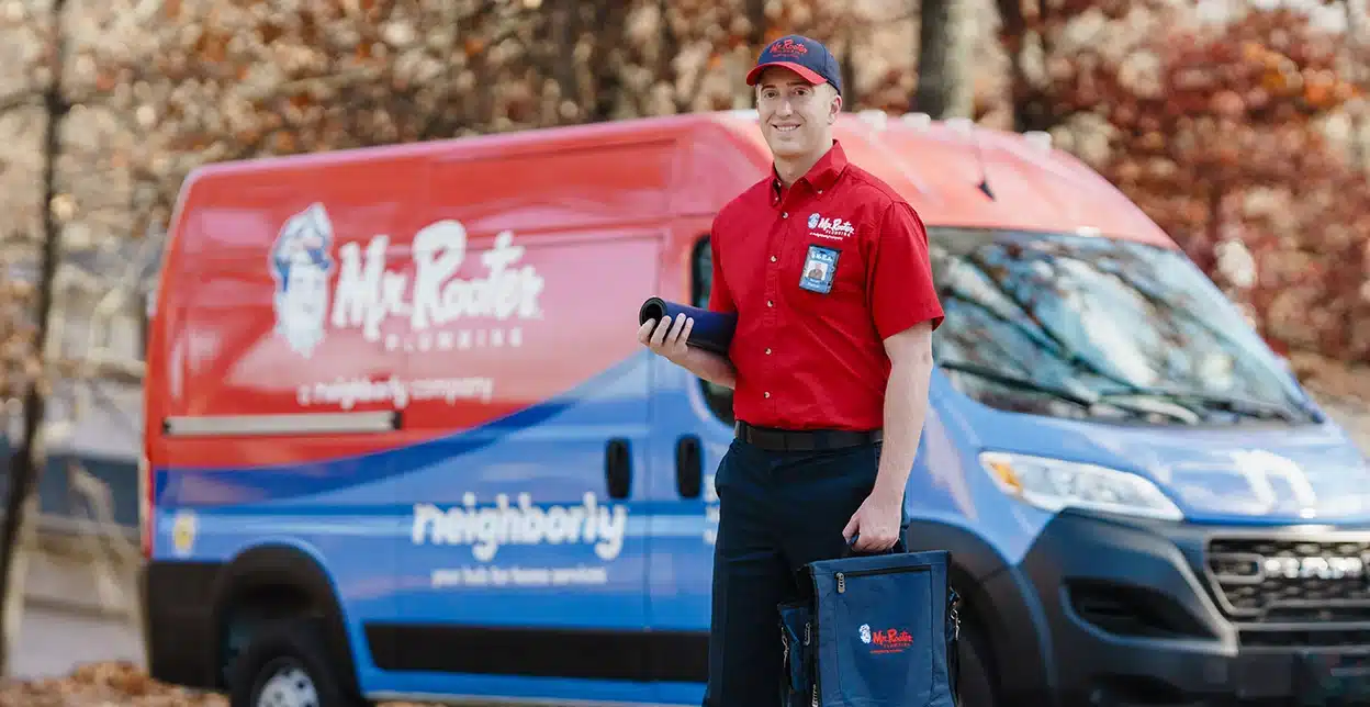 Mr. Rooter technician standing in front of a branded work van.