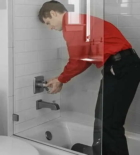 Male Mr. Rooter technician fixing bathtub faucet.