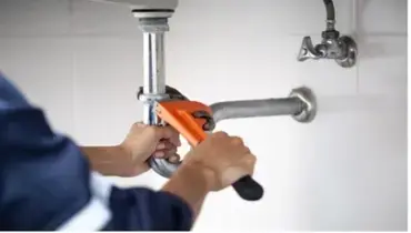 A plumber uses a monkey wrench to tighten a joint on a metal pipe. | Mr. Rooter Plumbing of Virginia Beach