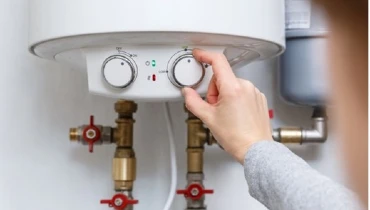 A woman’s hand turns a knob on an electric water heater. | Mr. Rooter Plumbing of The Oakland-Berkeley Area
