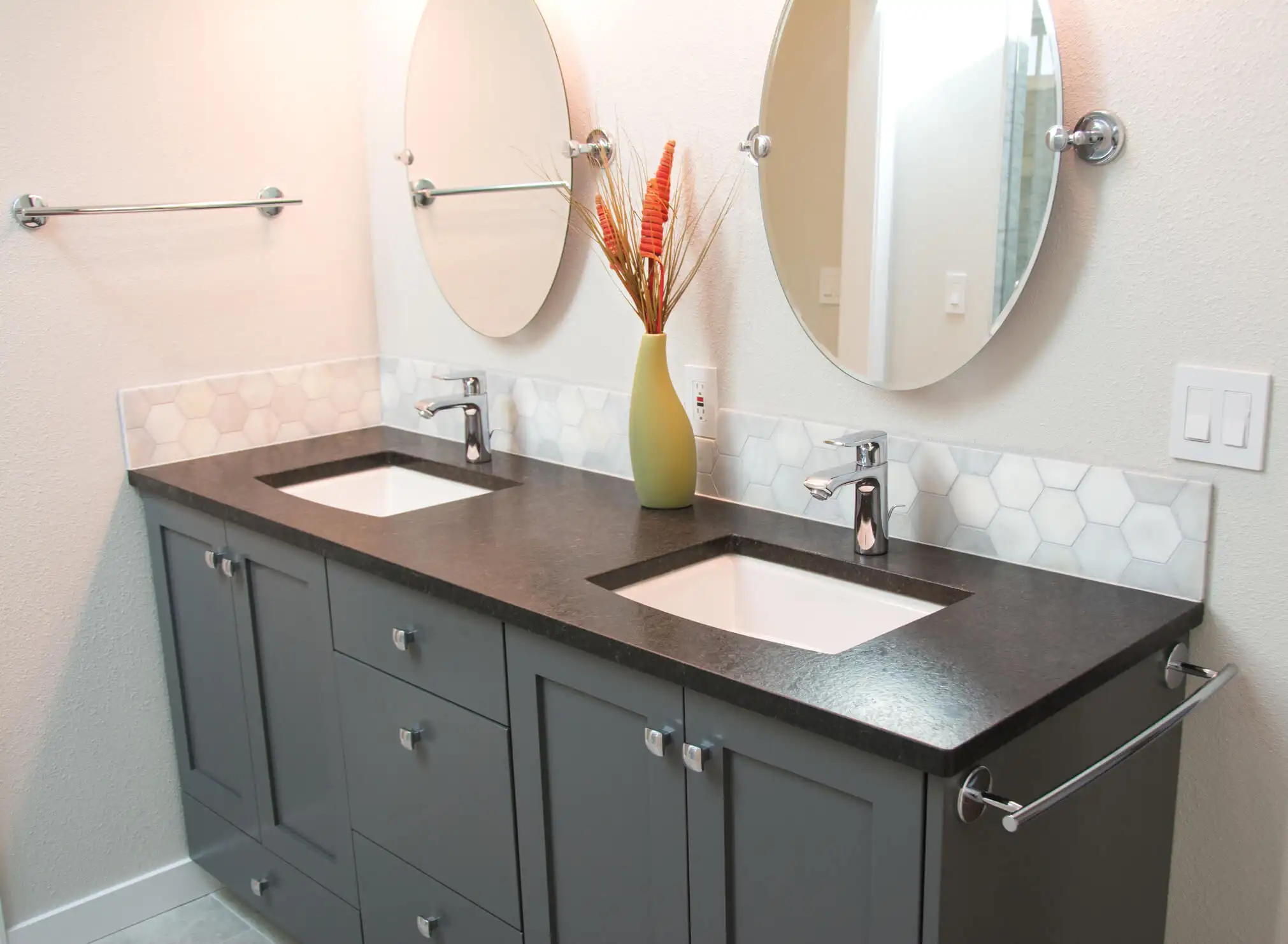 Black bathroom vanity with two sinks and two round mirrors on the gray wall