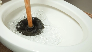 A plunger working to clear a clogged toilet drain.