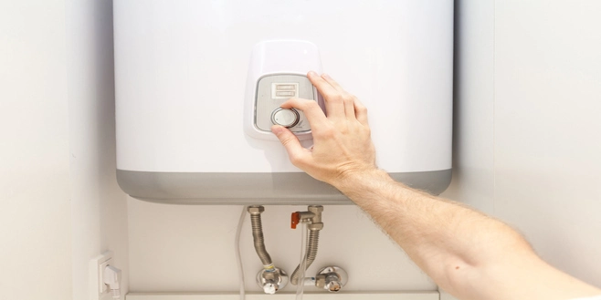 Close-up of a man's hands setting the temperature of an electric water heater.