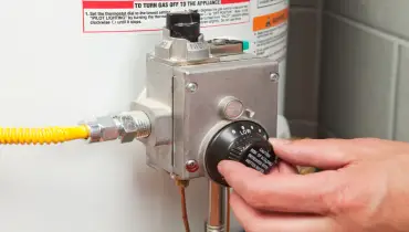 Hand Turning Down Water Heater Thermostat