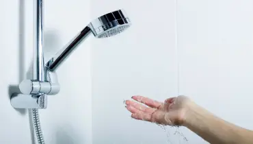 A hand reaching out to a running shower, checking the water temperature.