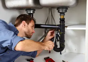 Man fixing pipes under a sink