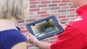 A service professional and a customer watching a video inspection of a sewer line.