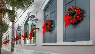 Decorative wreaths hang on a historic building in Charleston, South Carolina.