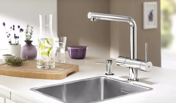 Lime water on a kitchen counter with a chrome Grohe kitchen faucet.