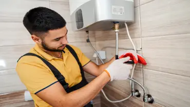 A plumber adjusts a line on a gas boiler.