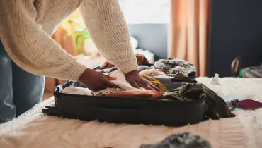 a woman packing her things into a suitcase at home