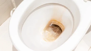 A toilet with rust stains accumulating in the bowl.