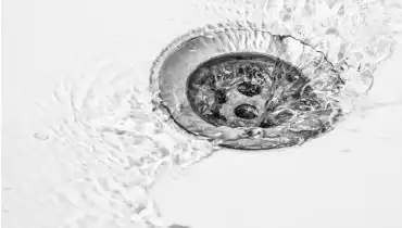 Clear water flows freely down a drain in a white sink. | Mr. Rooter® Plumbing of Virginia Beach