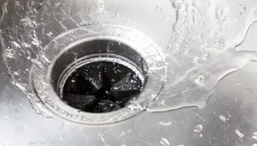 Water flows into a garbage disposal in a stainless steel sink. | Mr. Rooter Plumbing of Virginia Beach