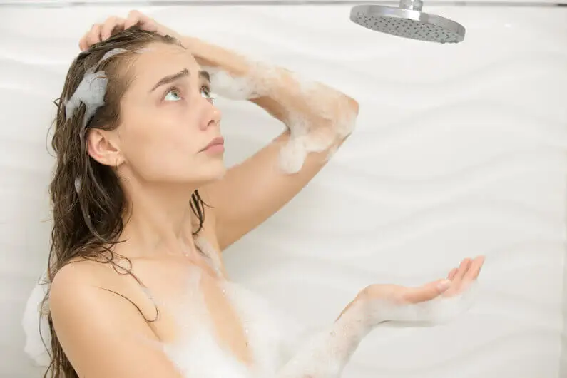 Confused woman covered in soap in a waterless shower