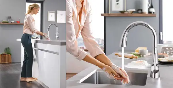 A homeowner washing their hands in the kitchen using foot control technology.