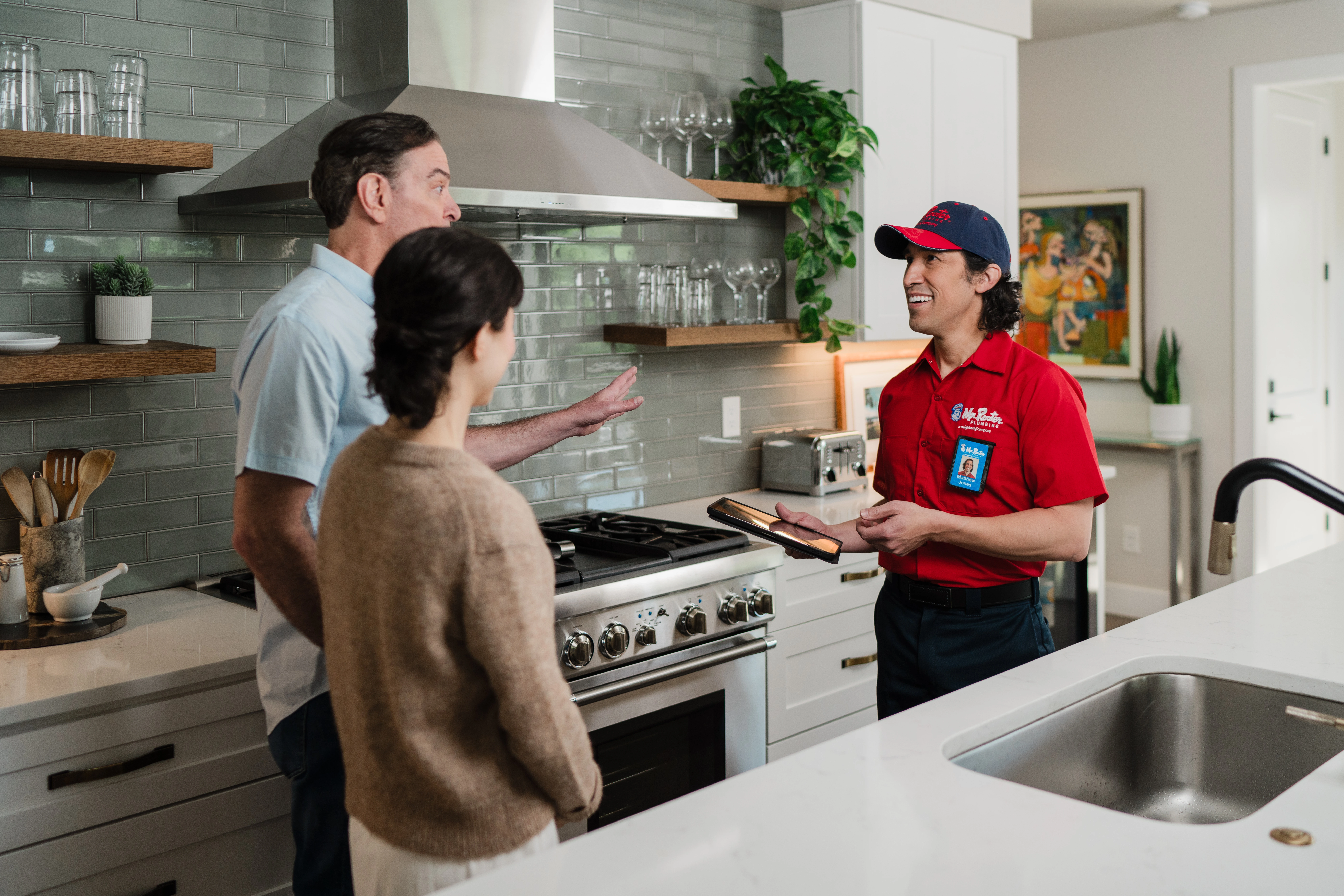 A Mr. Rooter Plumbing service professional walking homeowners through the results of a residential plumbing inspection.