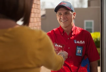 Mr. Rooter professional and experienced plumber smiling and handing homeowner his business card