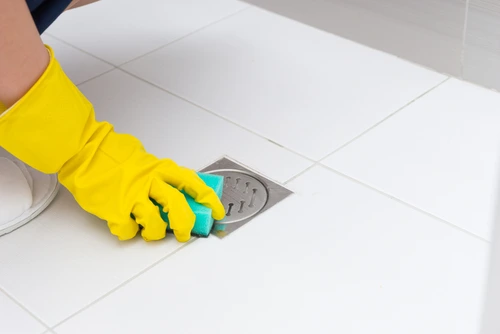 Homeowner gently cleaning a floor drain.
