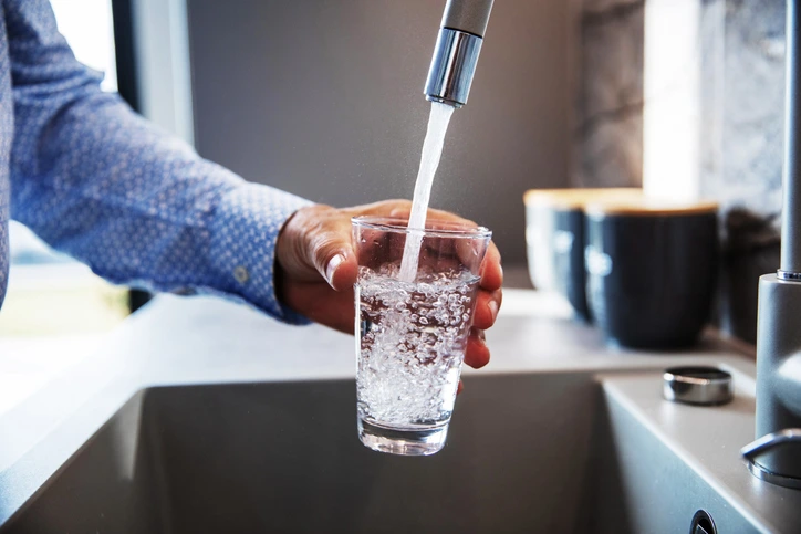 A person fills a glass with water from their kitchen faucet. | Mr. Rooter® Plumbing of Southeast Georgia