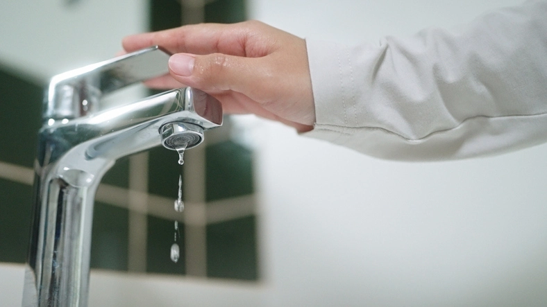Close-up hand turning on or off faucet in bathroom | Mr. Rooter Plumbing of Yavapai, Coconino, and Maricopa Counties