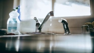 A close-up of a kitchen faucet with water dripping out, indicating a leak. | Mr. Rooter® Plumbing of South Jersey.