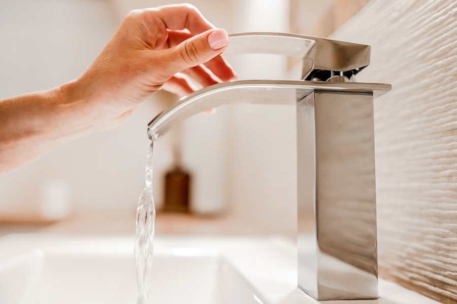 A woman testing a modern faucet after cartridge replacement to make sure it works.