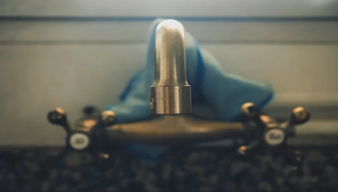 Close-up of a vintage brass faucet with a blue cloth draped in the background.