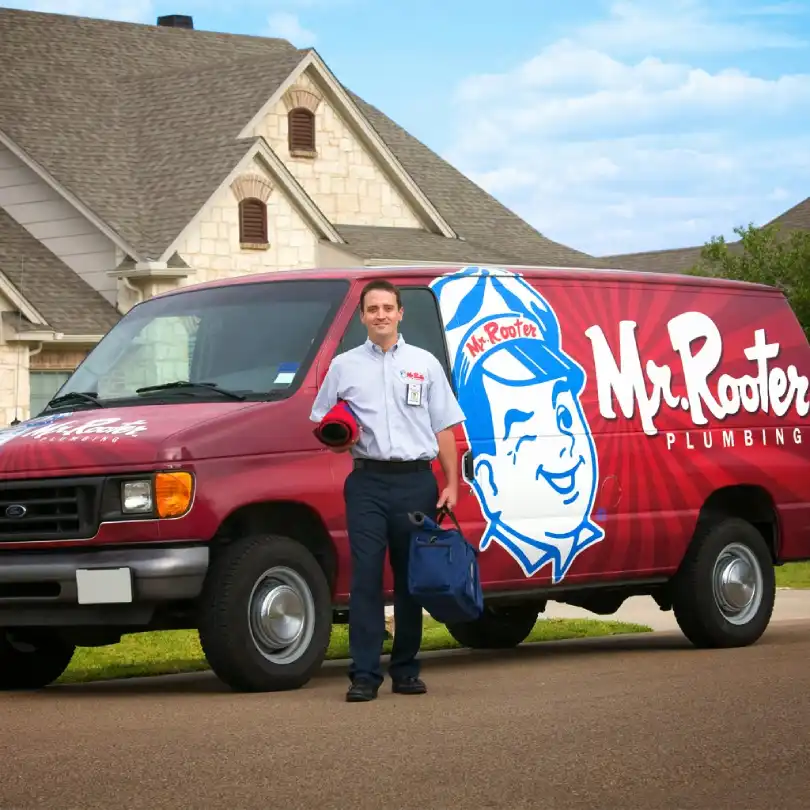 A San Antonio plumber carrying tools from a work van branded with the Mr. Rooter logo.