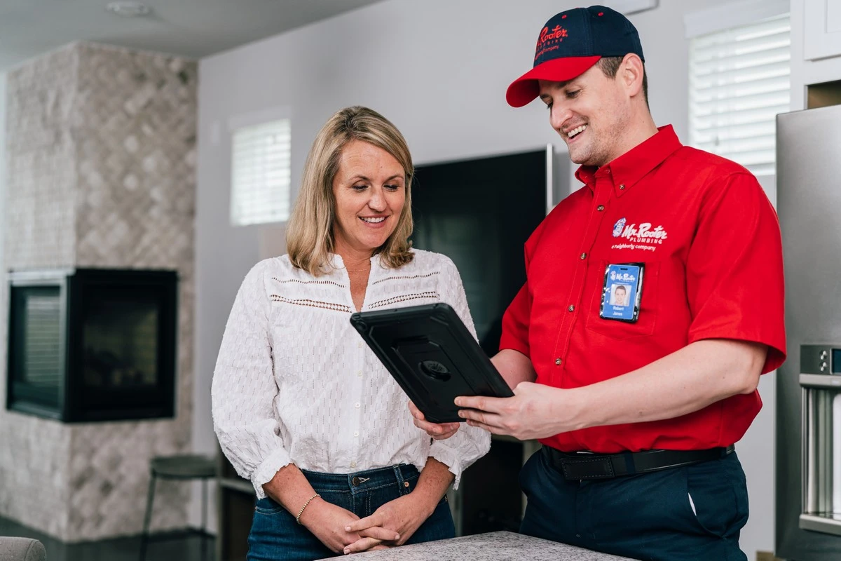 A plumber from Mr. Rooter Plumbing showing a homeowner about plumbing in Columbia, SC on an electronic tablet.