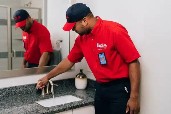 Mr. Rooter Plumber runs water in sink after drain cleaning.
