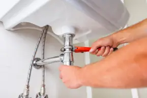 plumber completing plumbing repair on bathroom sink