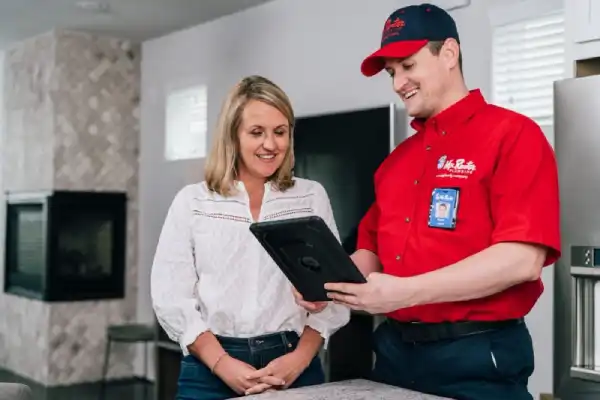 Mr. Rooter plumber and client smiling while looking at tablet in client's home.