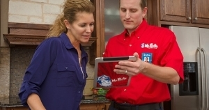 Mr. Rooter tech holding an tablet discussing drain pipe installation in Rochester, MN with a customer