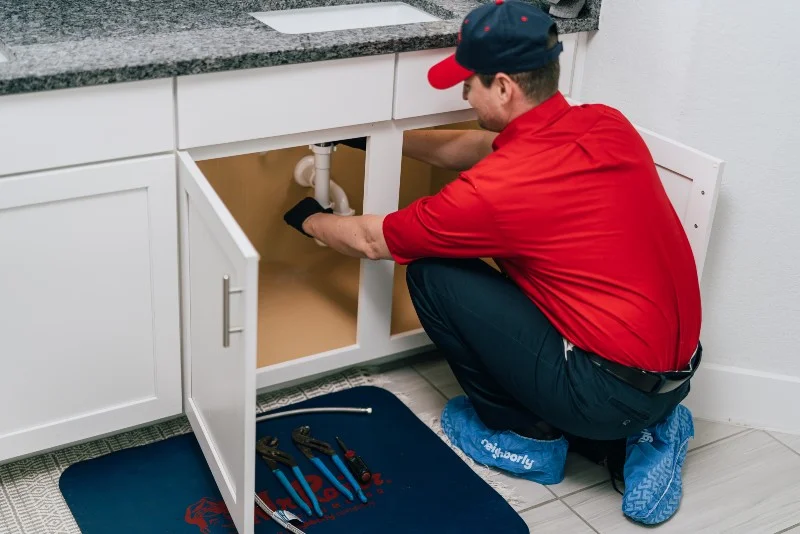 Mr. Rooter plumber repairing a clogged drain under a sink