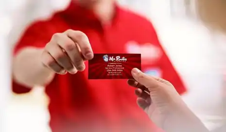 A Mr. Rooter Plumbing service professional handing a business card to a customer