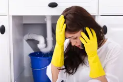 Distressed woman on phone with leaking pipe in the background